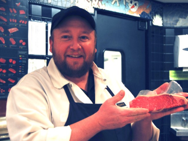 A butcher at the Webster Groves Straub's location holding a cut of prime strip.