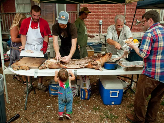 Brad "Mort" Munger (left) and John Joern (right) carve the first of two roasted pigs at the Off Broadway Pig Roast on Sunday.