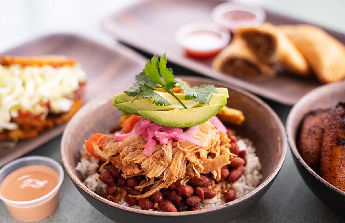 Pollo Guisado with braised chicken, vegetables, red beans, white rice, tostones, pickled onion and avocado.