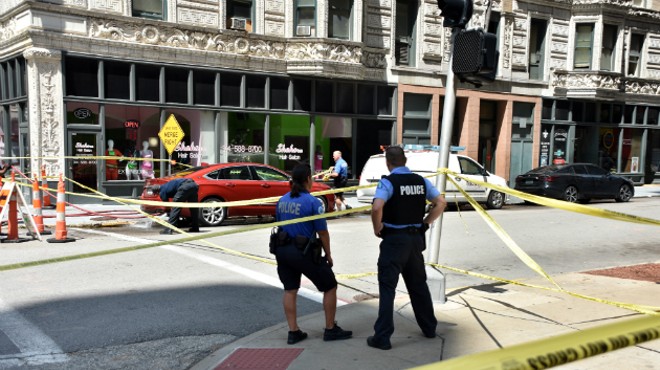 A St. Louis firefighter hoses blood off the street after a deadly shooting downtown.