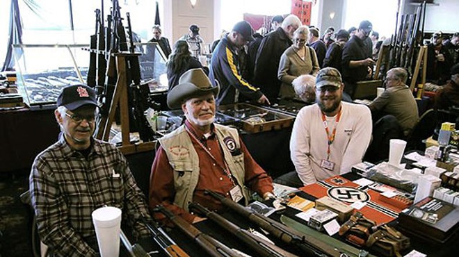 Alan Fasoldt (center) and father-son team Dominic Sr. (Left) and Dominic Jr. (Right) smile behind their collection of M1 Garands, ammo and war memorabilia.