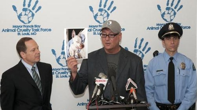 During a 2012 press conference, Randy Grim (center) holds up a photo of a dog that had been starved and thrown in a dumpster.