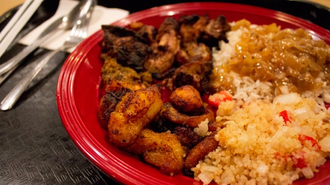 Alloco (fried plantain) and attieke (seasoned couscous-like cassava mixed with tomato, onion and hot pepper) on a jerk chicken plate.
