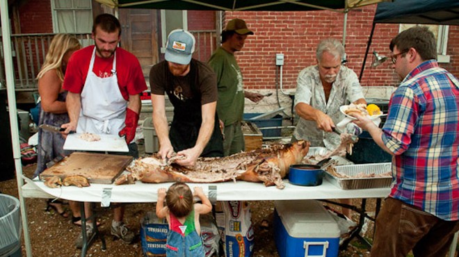 Brad "Mort" Munger (left) and John Joern (right) carve the first of two roasted pigs at the Off Broadway Pig Roast on Sunday.