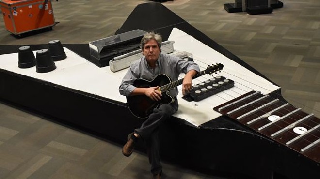 HP Newquist, executive director of the National Guitar Museum, sits atop the world's largest guitar.