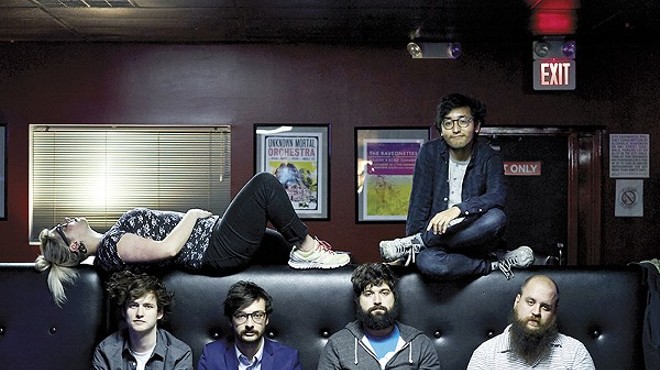 Foxing. Member Ricky Sampson sits on the top of the couch.