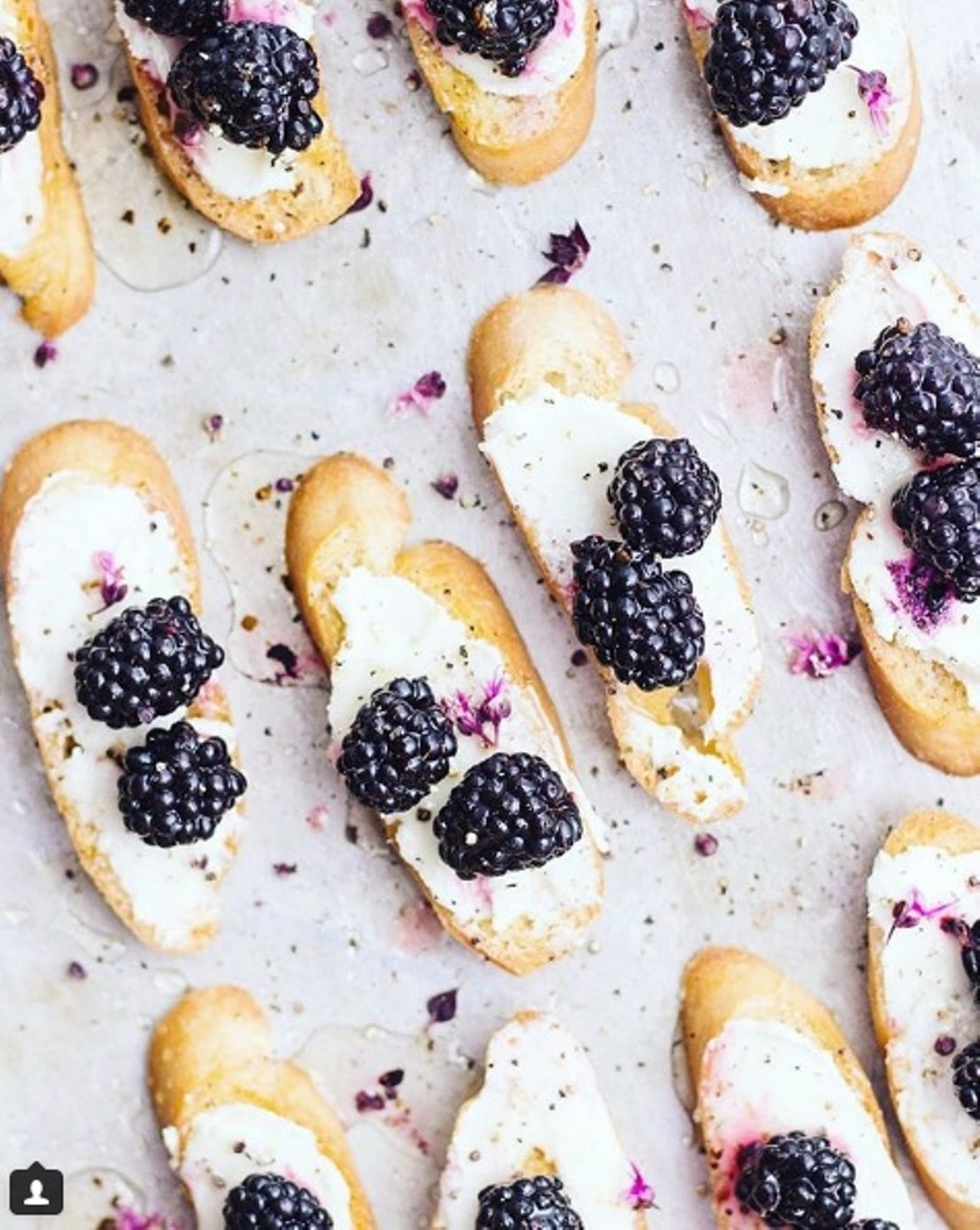 Goat cheese toast with quick-pickled blackberries, truffle honey and basil blossoms. Photo courtesy of Instagram / withfoodandlove.