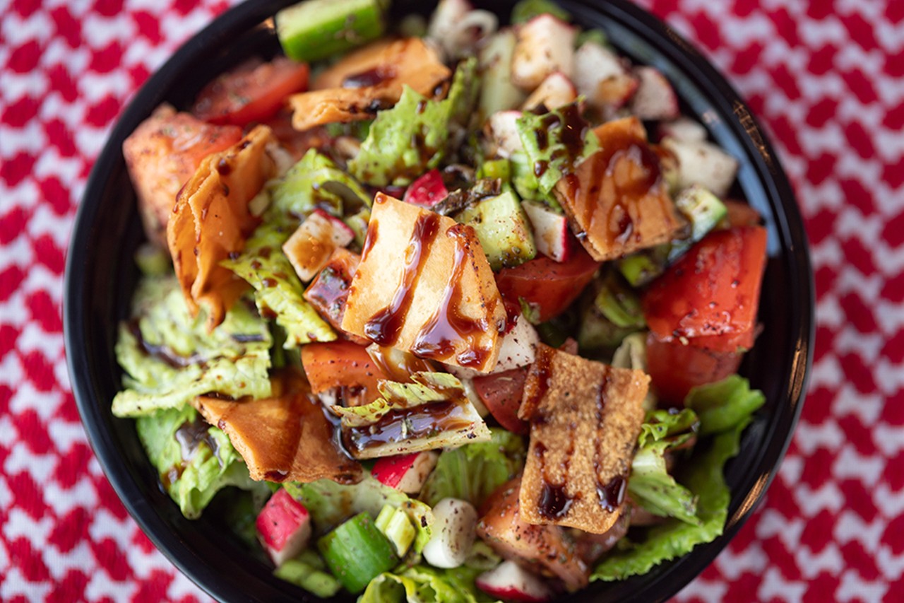 Fattoush salad with romaine, tomatoes, cucumbers and green onions, topped with pita chips, olive oil lemon dressing and pomegranate molasses.