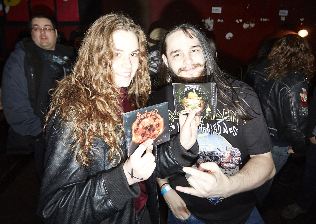 Sarah Donnabhain and Damien Hubbard showing off albums from the bands SunLord and Anvil.