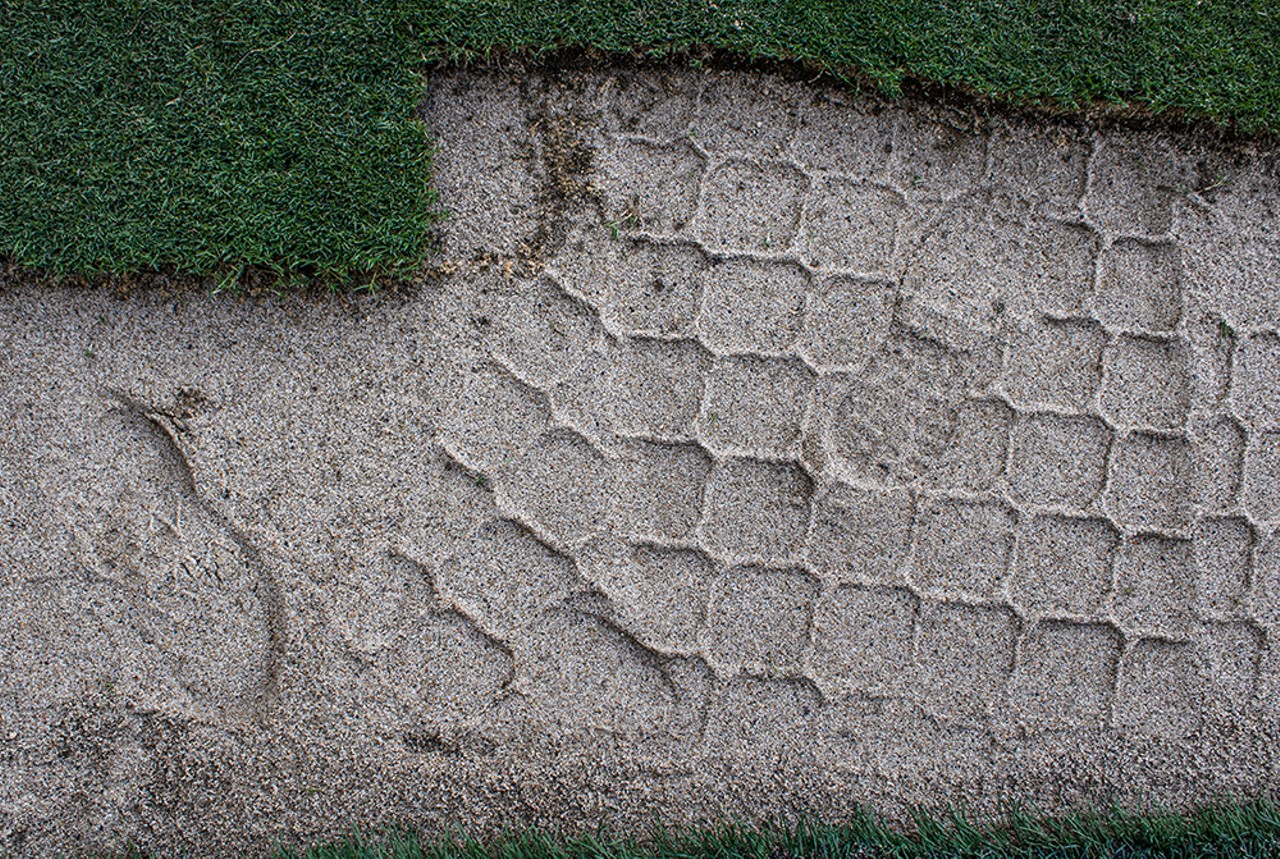 Footprints are imprinted in a compacted layer of sand and dirt.