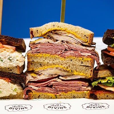 A selection of items from Deli Divine: chicken salad sandwich, smoked turkey and pastrami sandwich, and Manek sandwich.