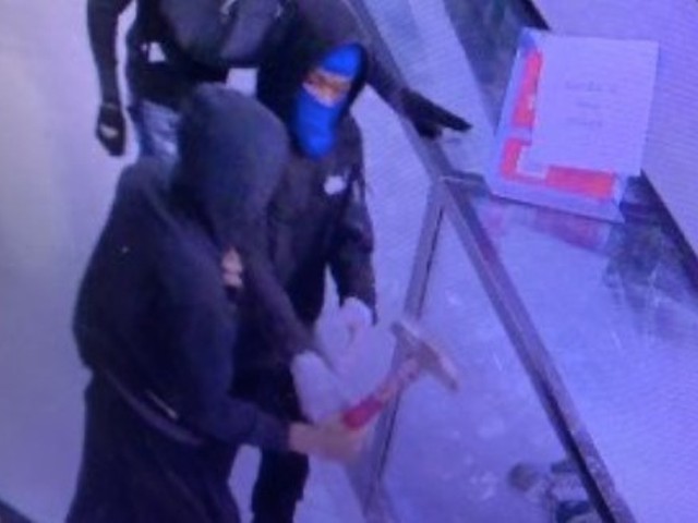 A still from surveillance video showing a gun store robbery in progress.