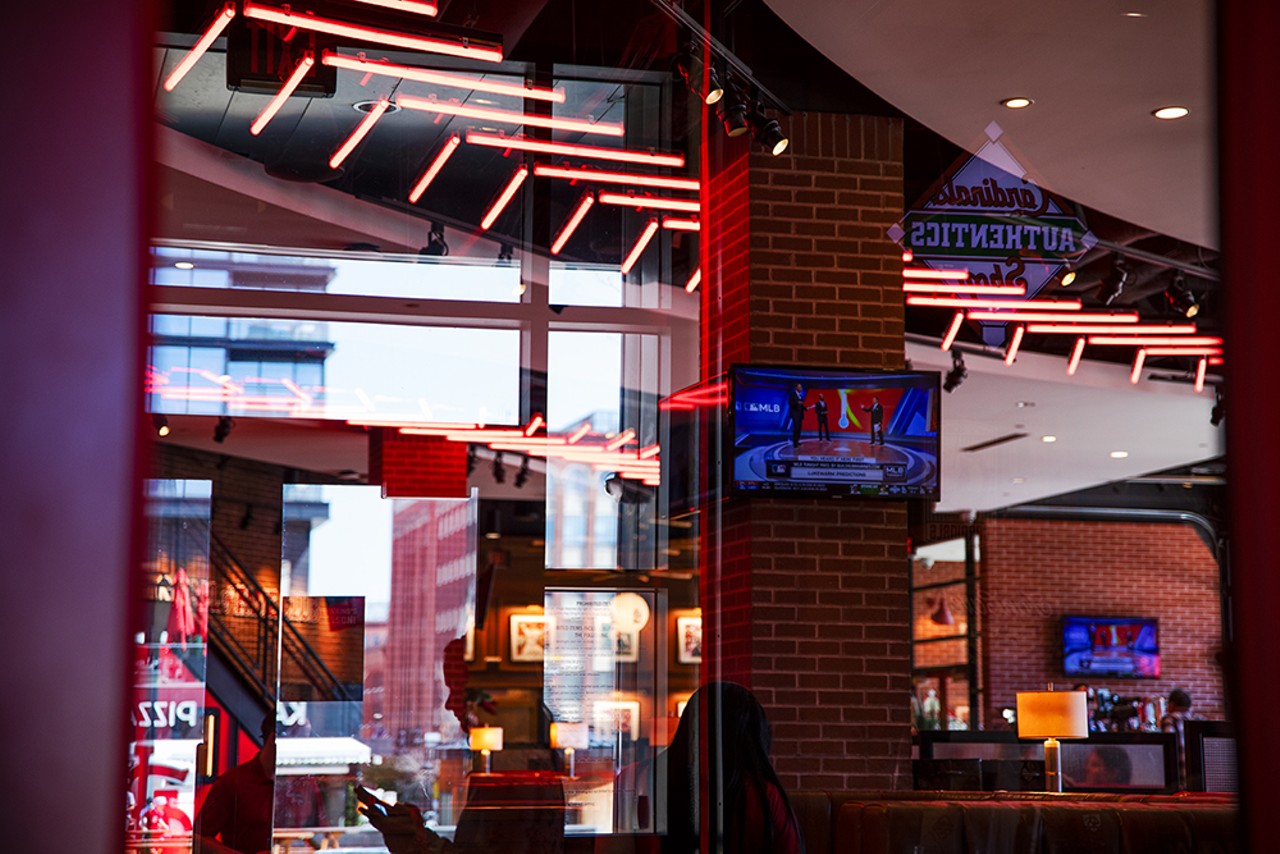 Scenes from Ballpark Village reflect off the windows inside the Cardinals Authentic Shop.
