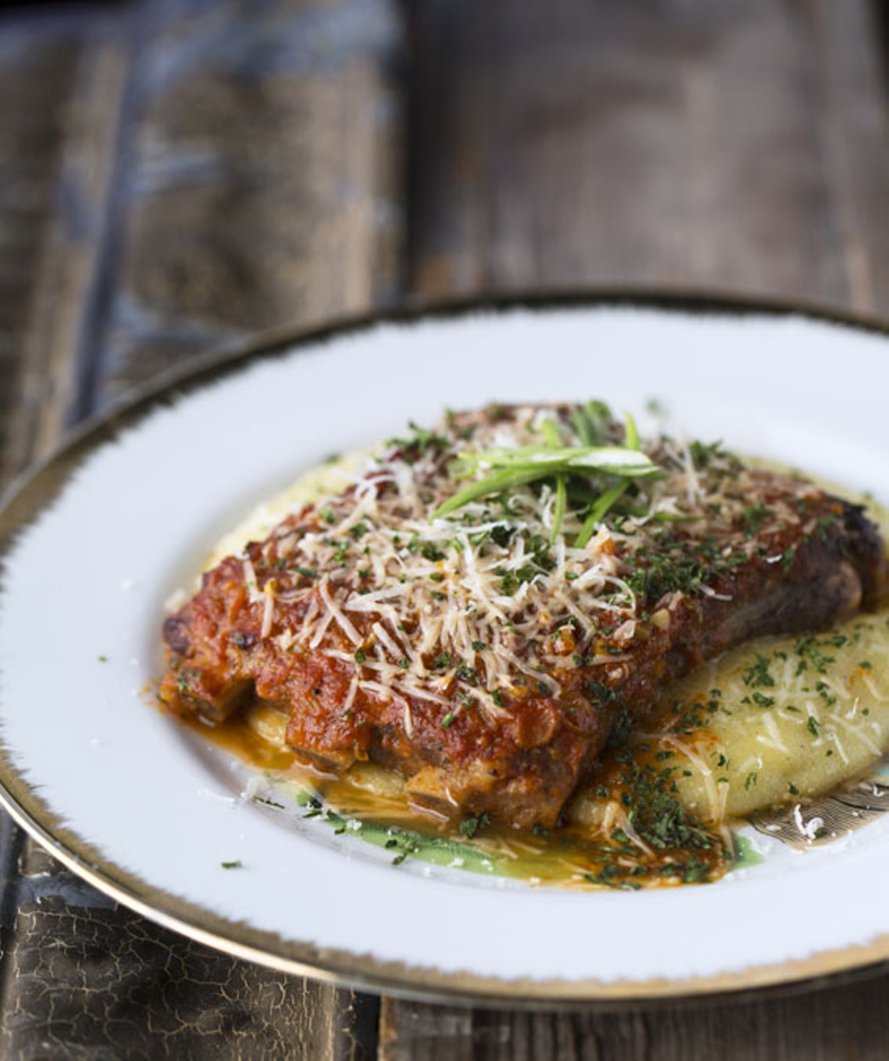 The St. Louis-cut pork ribs are brined overnight and braised in housemade bourbon marinara, then broiled and topped with fresh parmigiano and scallions.