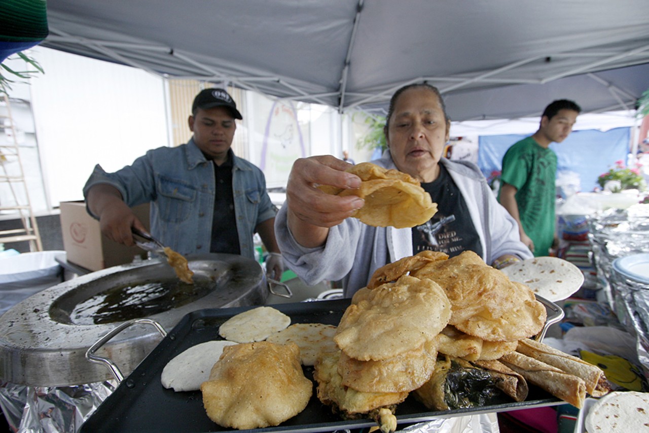 A woman grabs a fried masa to make a sope, a traditional Mexican dish topped with meat, refried beans, cheese, lettuce, onions and salsa.