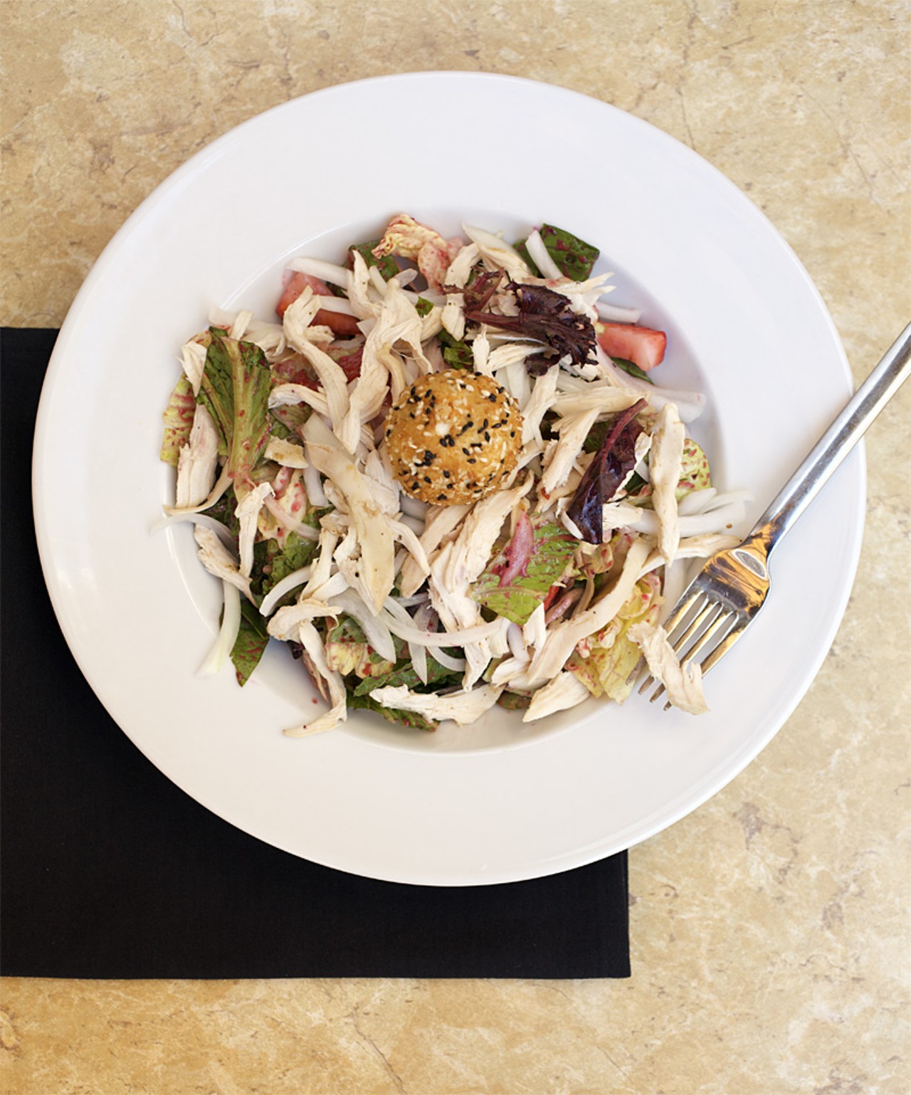 Copia's Goat Cheese Salad is mixed greens, roasted chicken, sweet onion, sliced strawberries tossed in cracked pepper berry vinaigrette. It is then topped with warm sesame encrusted goat cheese.