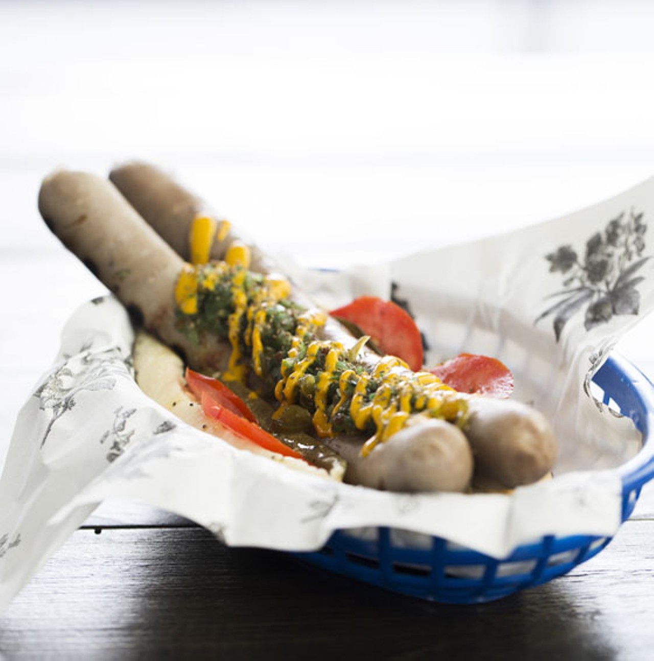 Housemade all-beef hot dog nestled in a poppy-seed bun and topped with yellow mustard, tomato, green relish, spicy peppers.