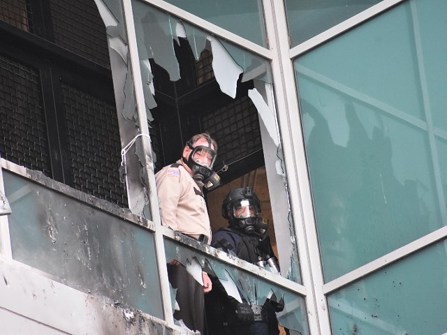 A St. Louis Sheriff's deputy and police SWAT supervisor look out of shattered window on February 6, 2021, at the City Justice Center.