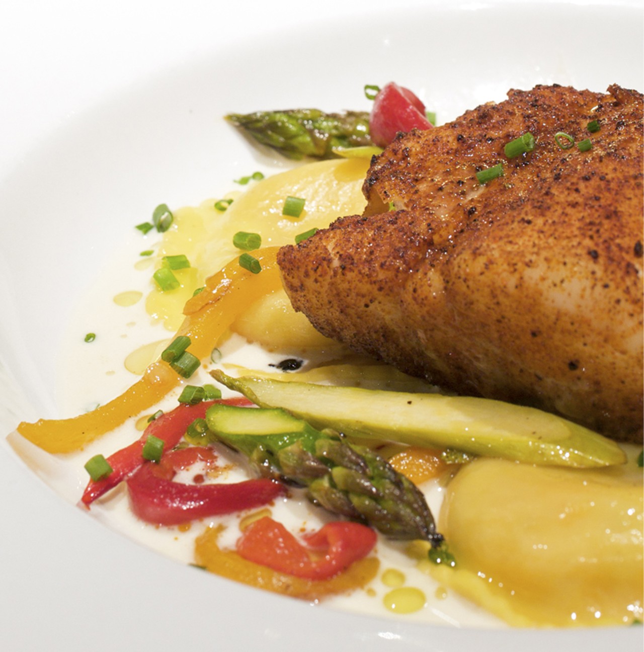 The chili-roasted Cod, one of the house specialties, is served with lobster ravioli, roasted peppers, grilled asparagus and Champagne sauce.