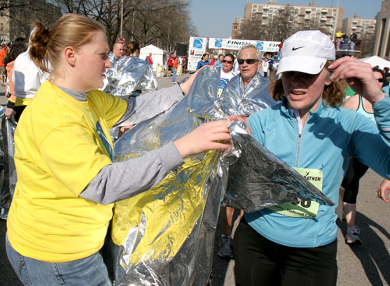 Go! St. Louis Marathon volunteer, Jamie Gaddy, applies mylar blankets to runners after crossing the finish line.  These foil blankets traps body heat to keep the body warm and prevent muscle stiffness.