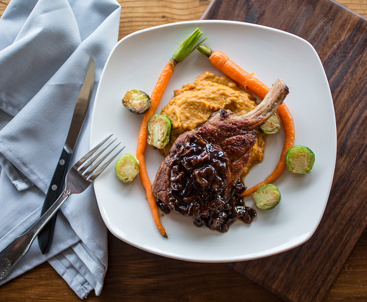 Deppe Farms' heritage-breed Duroc pork chop is served with Ozark Forest wild mushroom madeira sauce, Double Star Farms sweet potato and cauliflower mash, roasted baby carrots and Brussels sprouts.