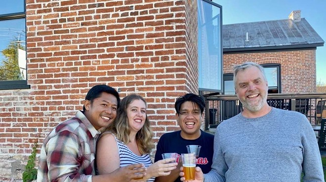 Joel Crespo, Rachel Alcantara, Arnold Alcantara and Brian Hardesty hold beverages in front of a brick house.