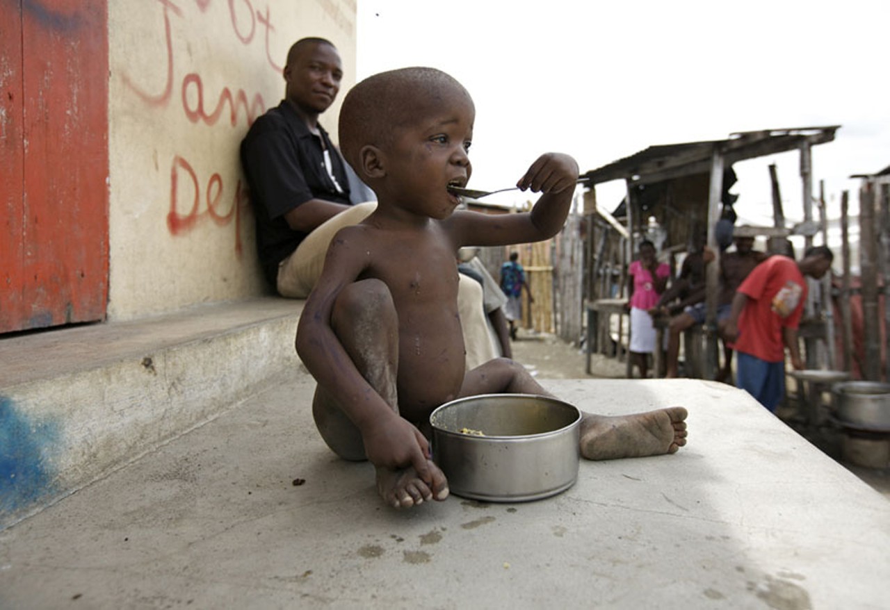 A young boy eats what he can in the slums of Cap-Haitien known as Shada.
