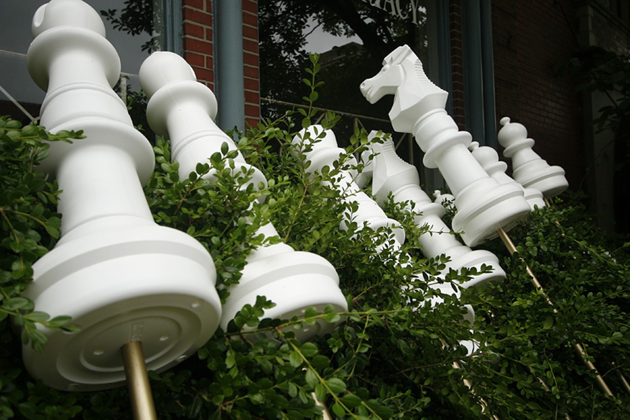 The oversized chess pieces players hold lay on bushes before the match.