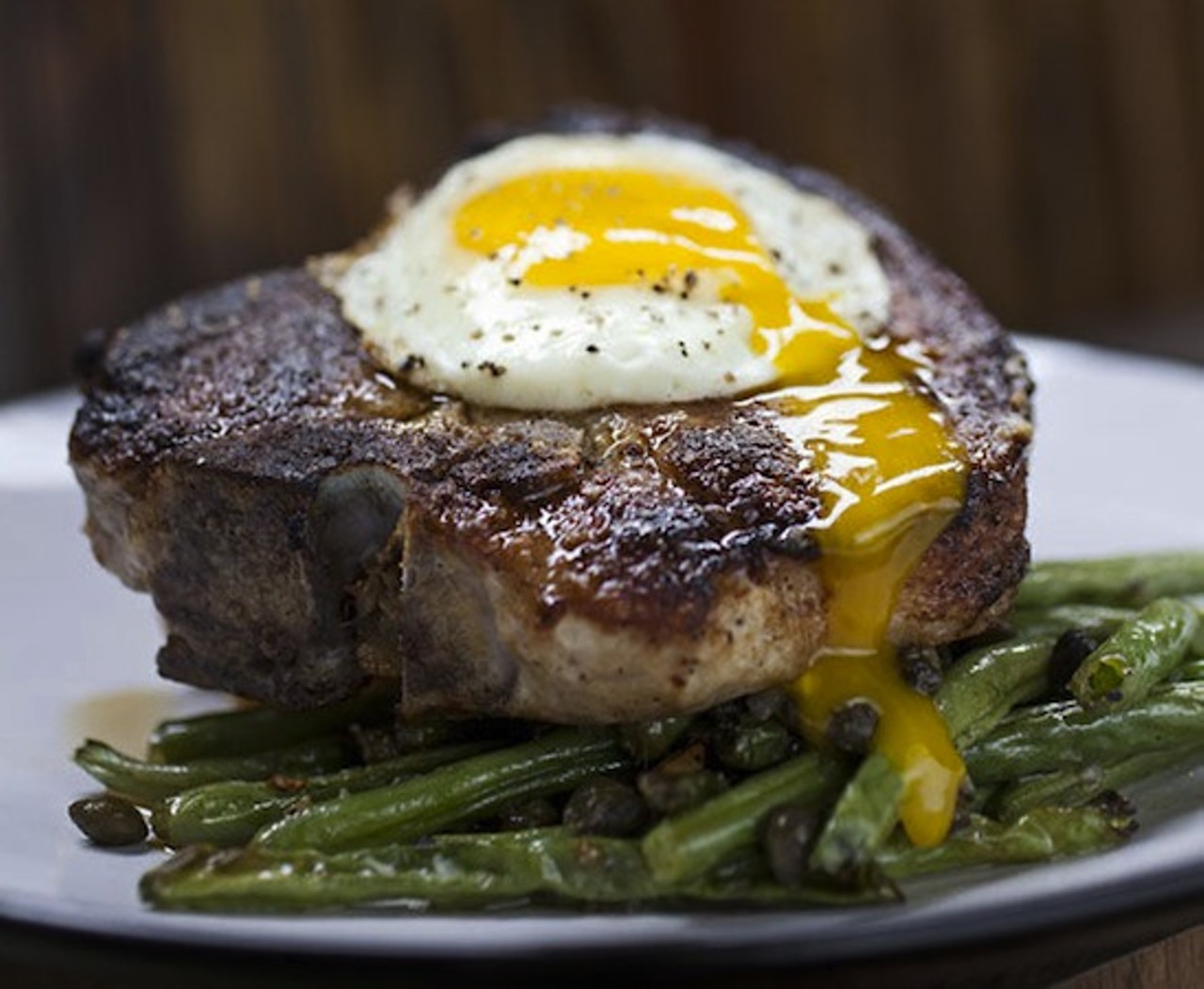 4. The "Pork Porterhouse" at Cleveland-Heath
The pork chop "porterhouse," topped with a sunny-side-up egg and served over jalape&ntilde;o-cheddar bread pudding, perfectly captures the Cleveland-Heath aesthetic of elevated comfort food.