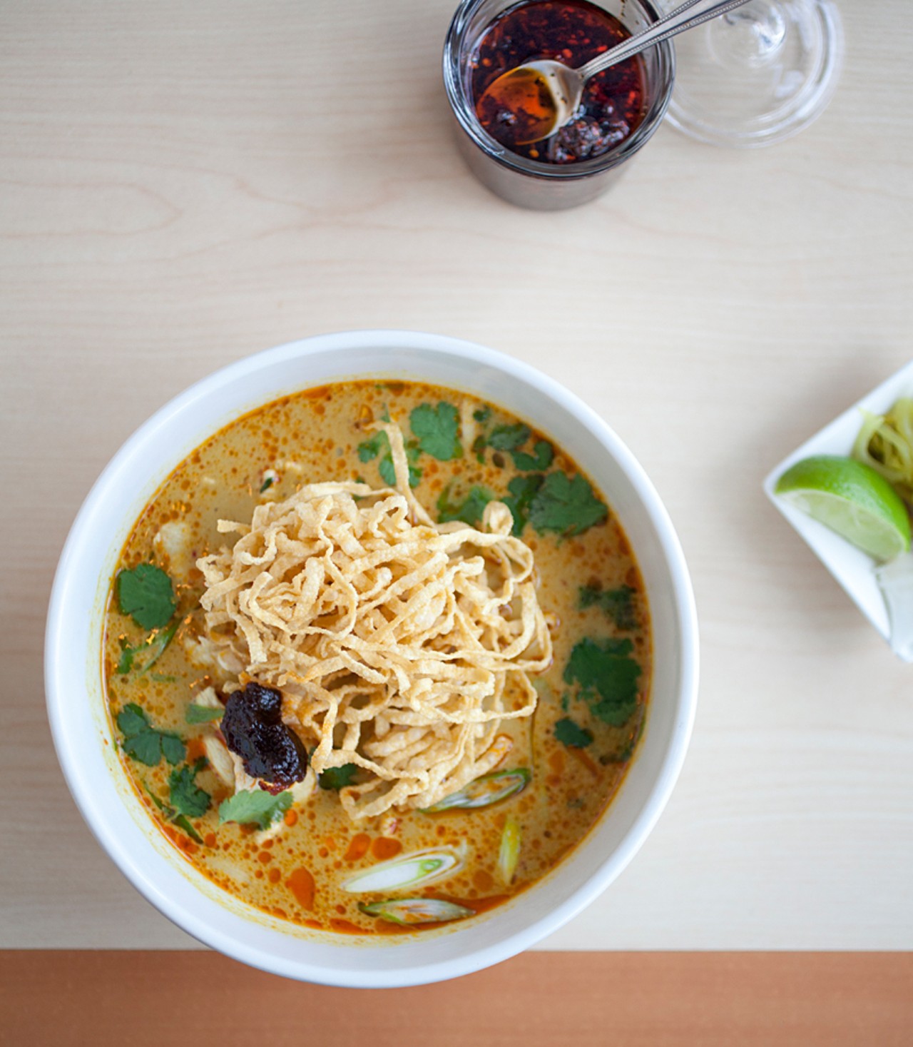 Khao Soi with chicken -- also available with beef or tofu -- is a northern Thai curry noodle soup made with curry paste and coconut milk. It is served with shallots, pickled mustard greens, crispy yellow noodles and roasted chili paste.