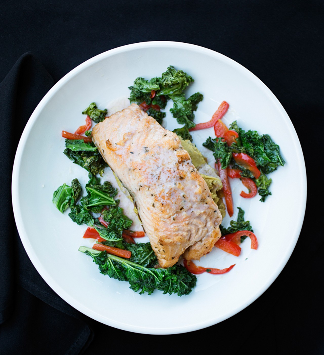 J Greene's pan-seared salmon is served with sauteed garlic kale and red peppers, chickpea puree, and a citrus beurre blanc.