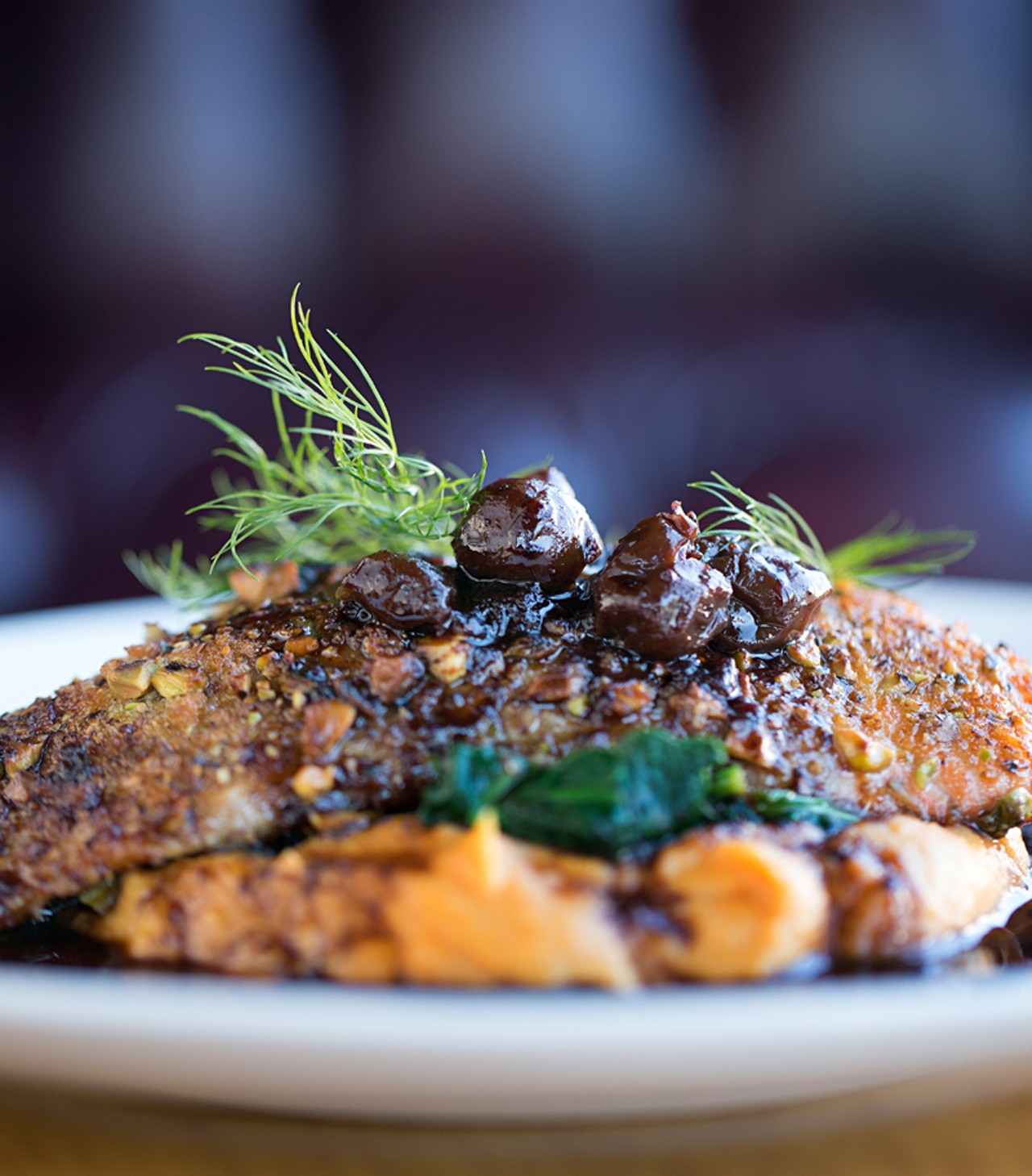 Pistachio-encrusted salmon with a sweet potato puree, served with sauteed spinach and a cherry-red wine sauce.