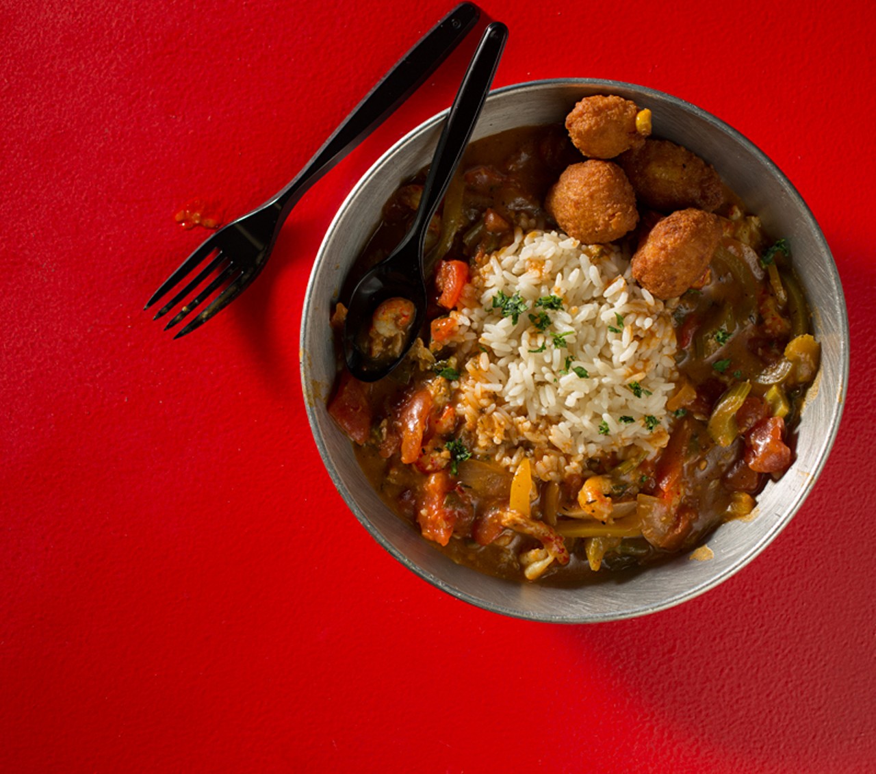 Etouffee is a creole dish with peppers, onions, celery. Here, it's shown with crawfish, and served over a bed of rice.