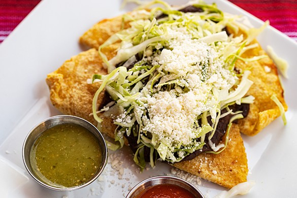 Empanadas fritas — two handmade fried corn tortillas stuffed with Oaxaca cheese or chicken, topped with refried black beans, cabbage, queso fresco and salsa.