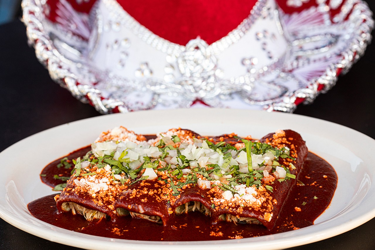 Enchiladas de mole with handmade corn tortillas filled with chicken in mole sauce, topped with onions and cilantro.