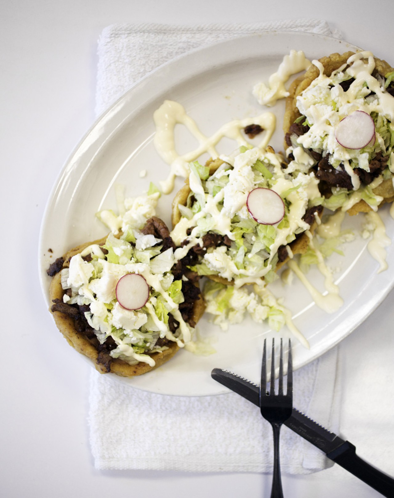 Sope is made with cornmeal, your choice of meat (shown here with beef), lettuce, Mexican sour cream, queso fresco and garnished with radishes.