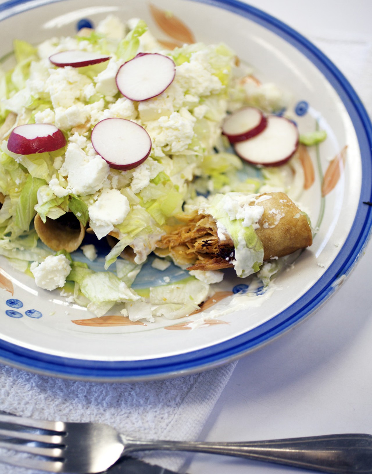 The Flautas are made with corn tortillas and your choice of meat. Here it has been prepared with chicken, and is served with lettuce, queso fresco and radishes.