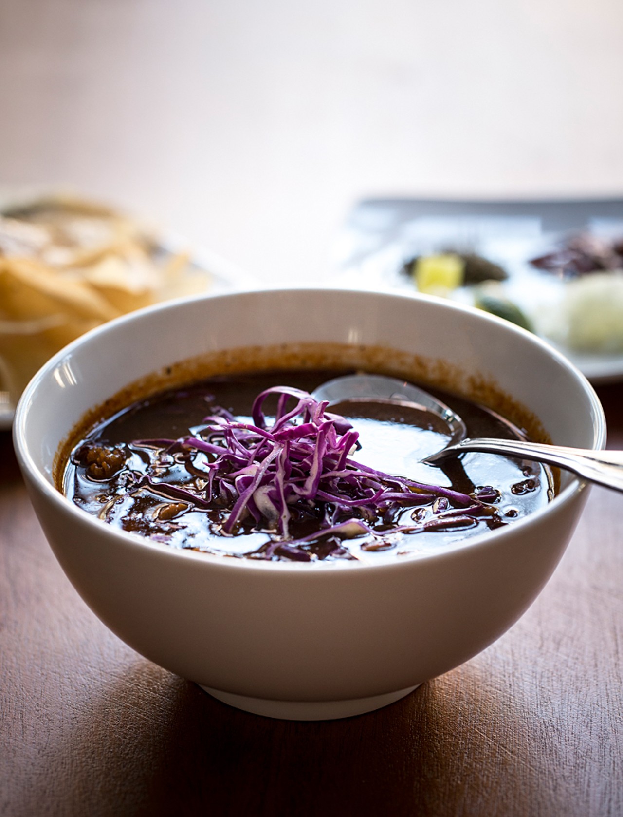 "Pozole Rojo" is a consomm&eacute; of arbol and ancho chiles served with crisped pulled pork, hominy and julienned cabbage.