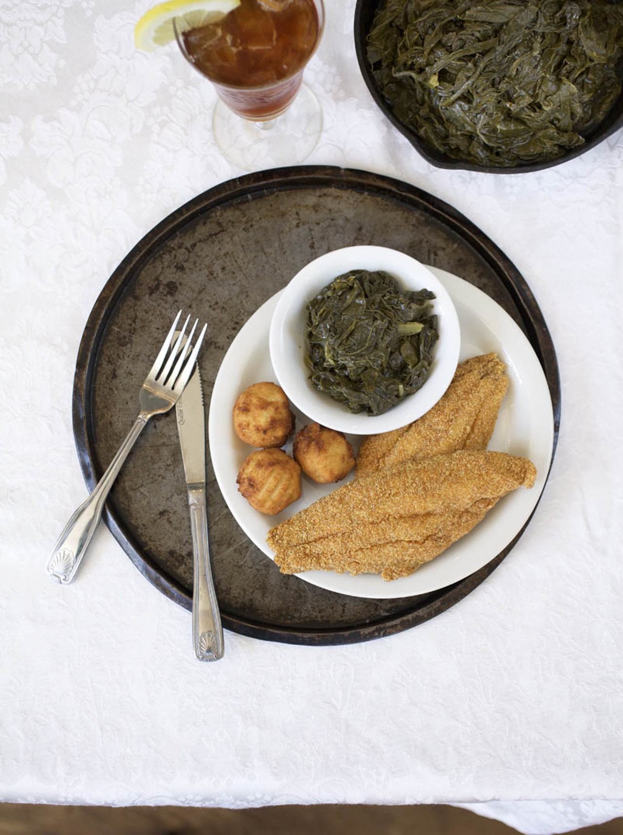 The Fingerlickin Fish comes with hushpuppies and another side of your choice. You have a choice of either catfish, fried or baked fresh tilapia filets. Here, it is shown with the catfish and the side choice of turnip greens. Also shown is the house sweet tea.