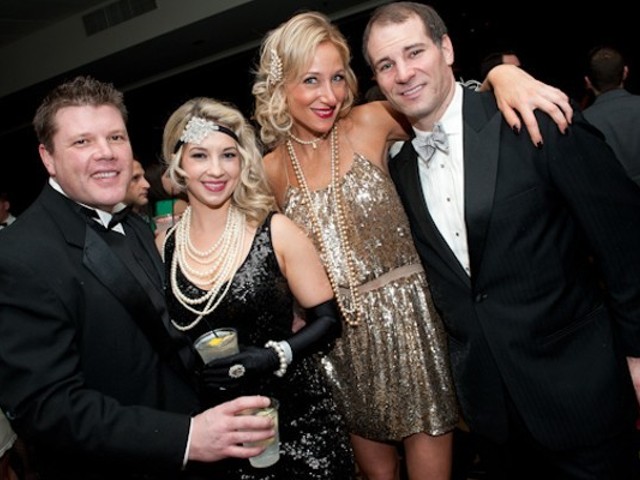 Four people dressed in 20s outfits pose for the camera.