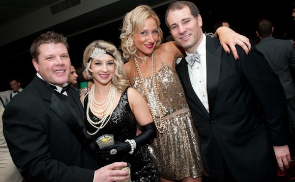 Four people dressed in 20s outfits pose for the camera.