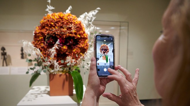 A person takes a photo of an orange flower display.