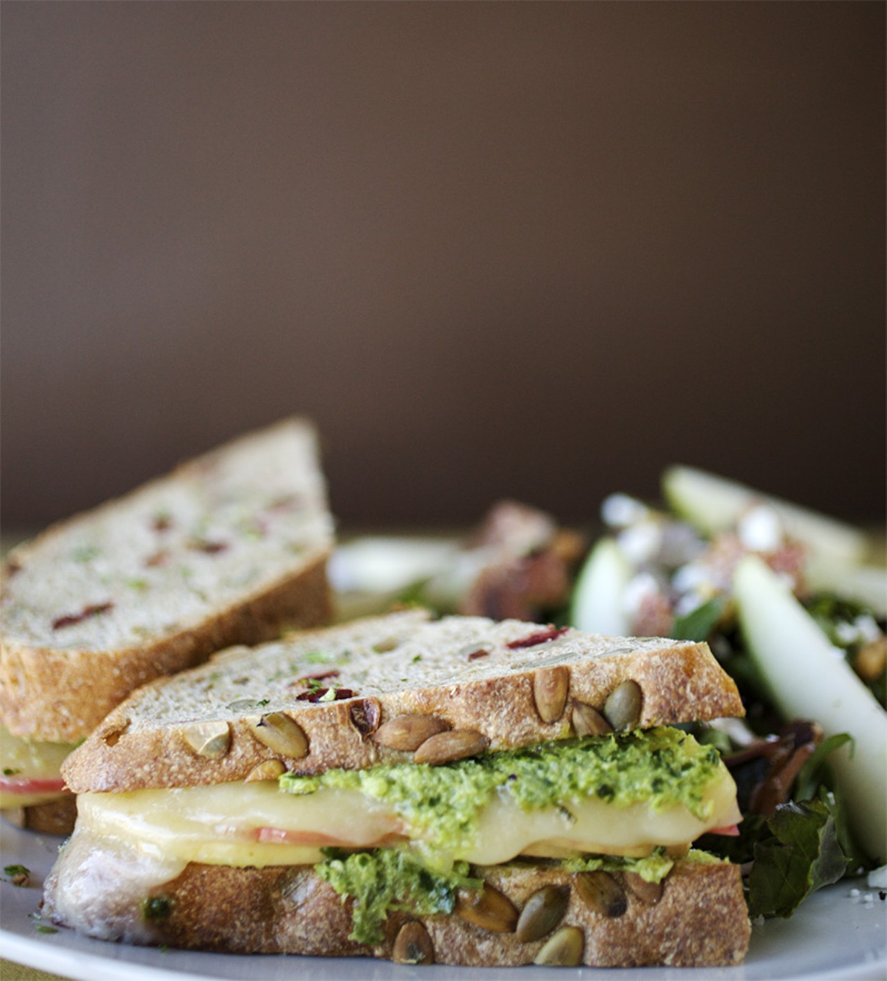 The Orchard Melt sandwich is made with thinly sliced organic apple, creamy havarti and celery pesto grilled on rustic pumpkin bread. Shown here with The Harvest salad.