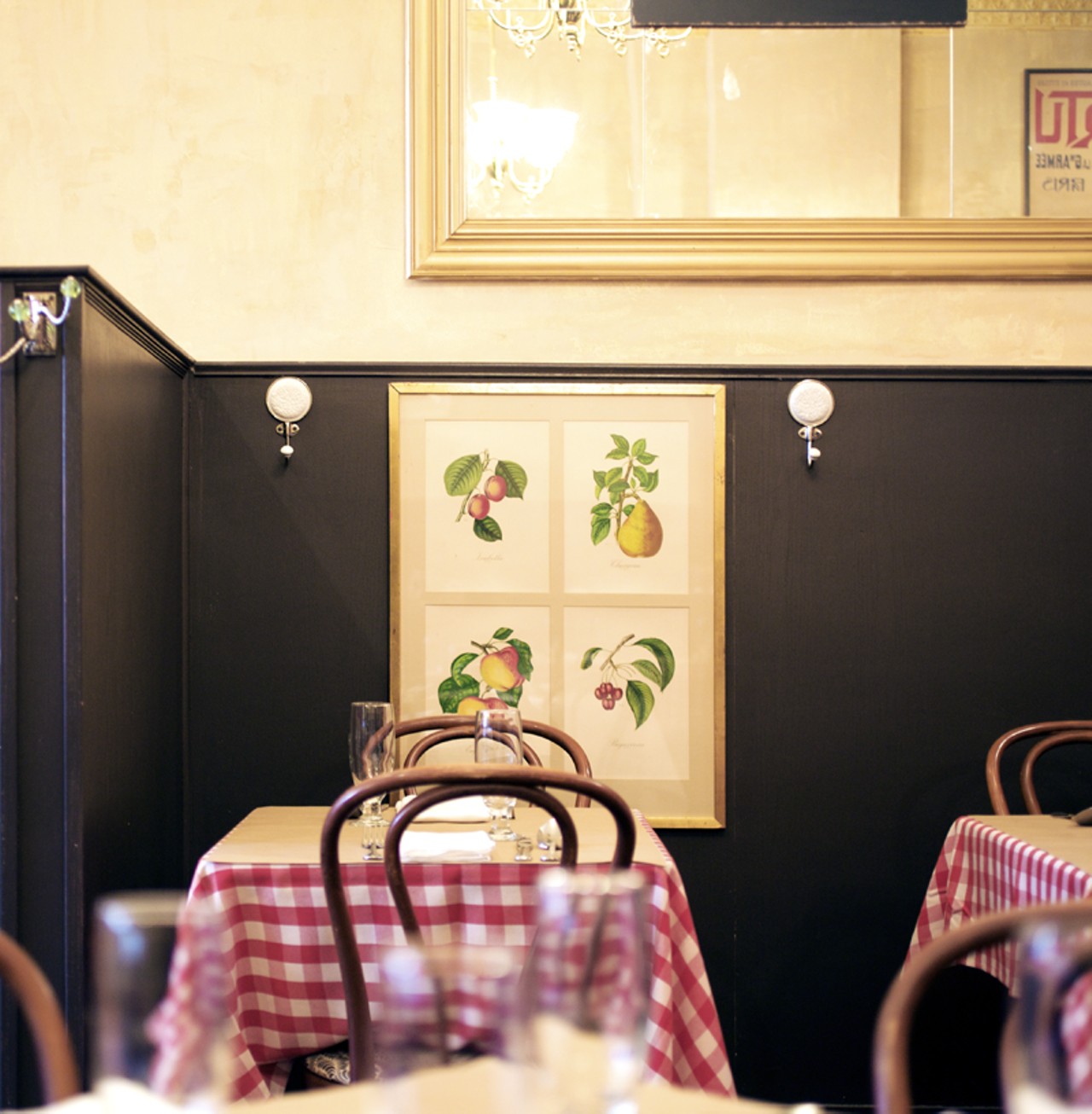 The red-and-white checkered table cloths, topped with brown butcher paper, and whimsical artwork make up the interior of Brasserie by Niche.
