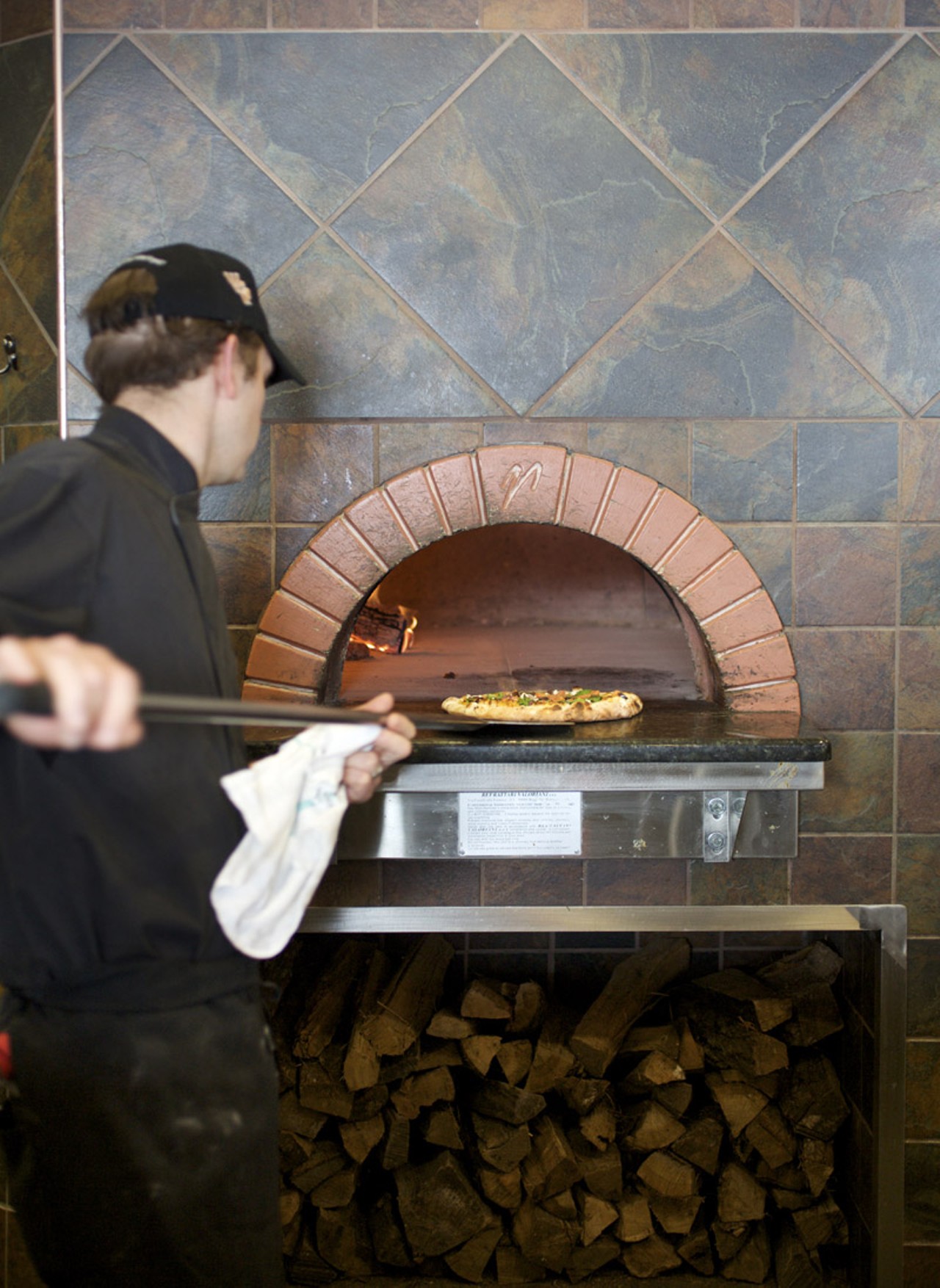 Owner/ Chef Patrick Thirion putting the pizza in the wood burning oven.