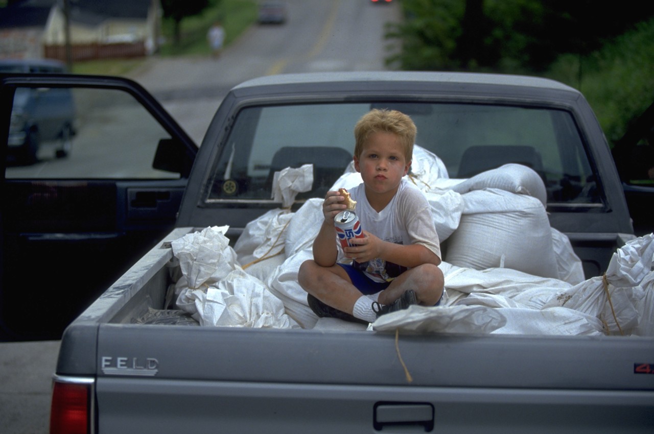 A kid sits atop sandbags in St. Charles.