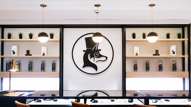 A logo of a fox in a hat overlooks a seating area with a glass case showing products.