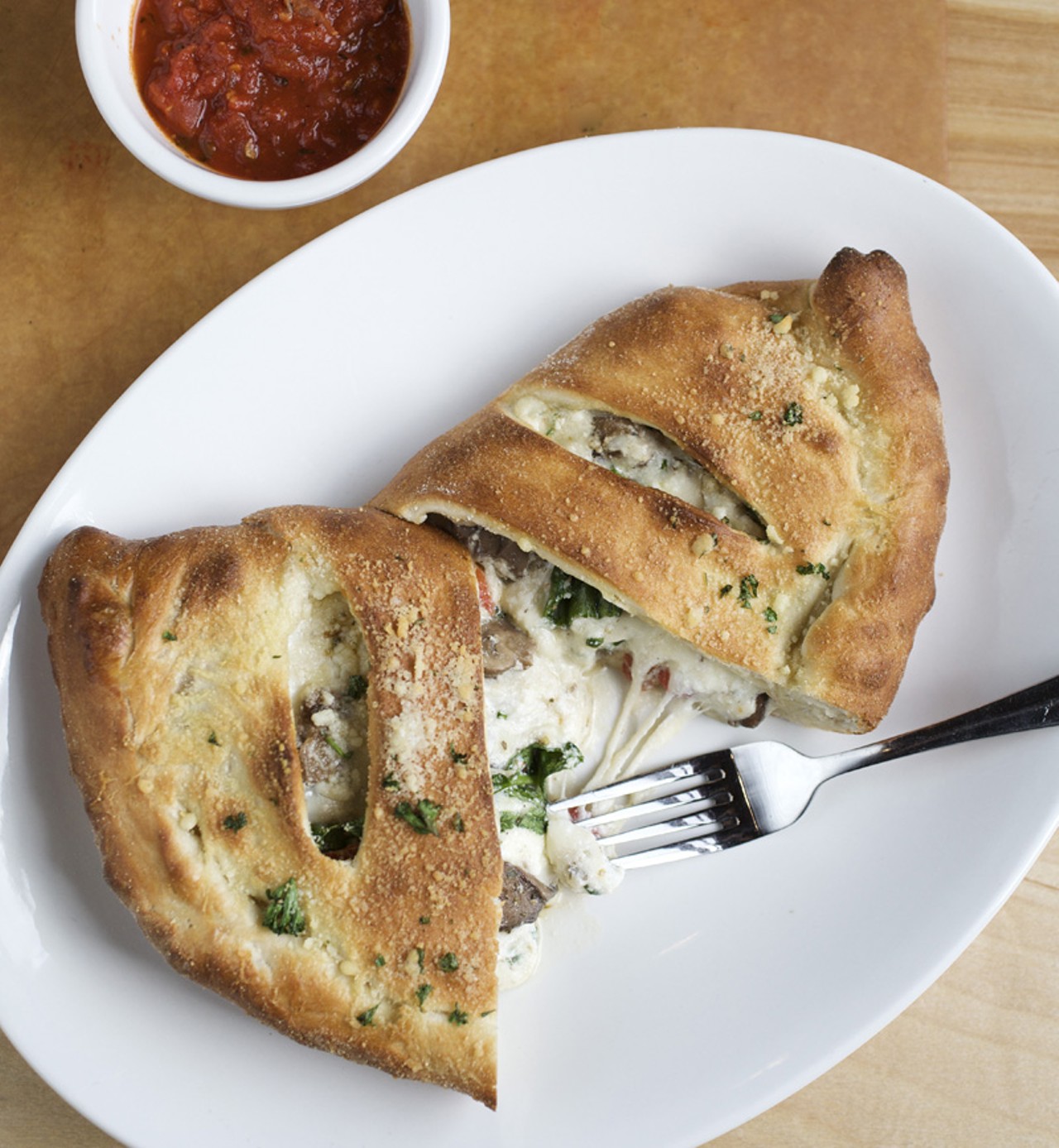 A Veggie Calzone - made with herb ricotta, wild mushrooms, spinach, roasted red peppers, caramelized onions, mozzerella and parmesan. Marinara sauce, on the side.