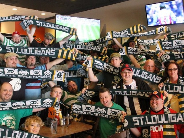 A group fo people hold "St. Louligans" scarves in a restaurant.