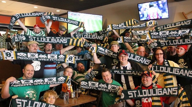 A group fo people hold "St. Louligans" scarves in a restaurant.